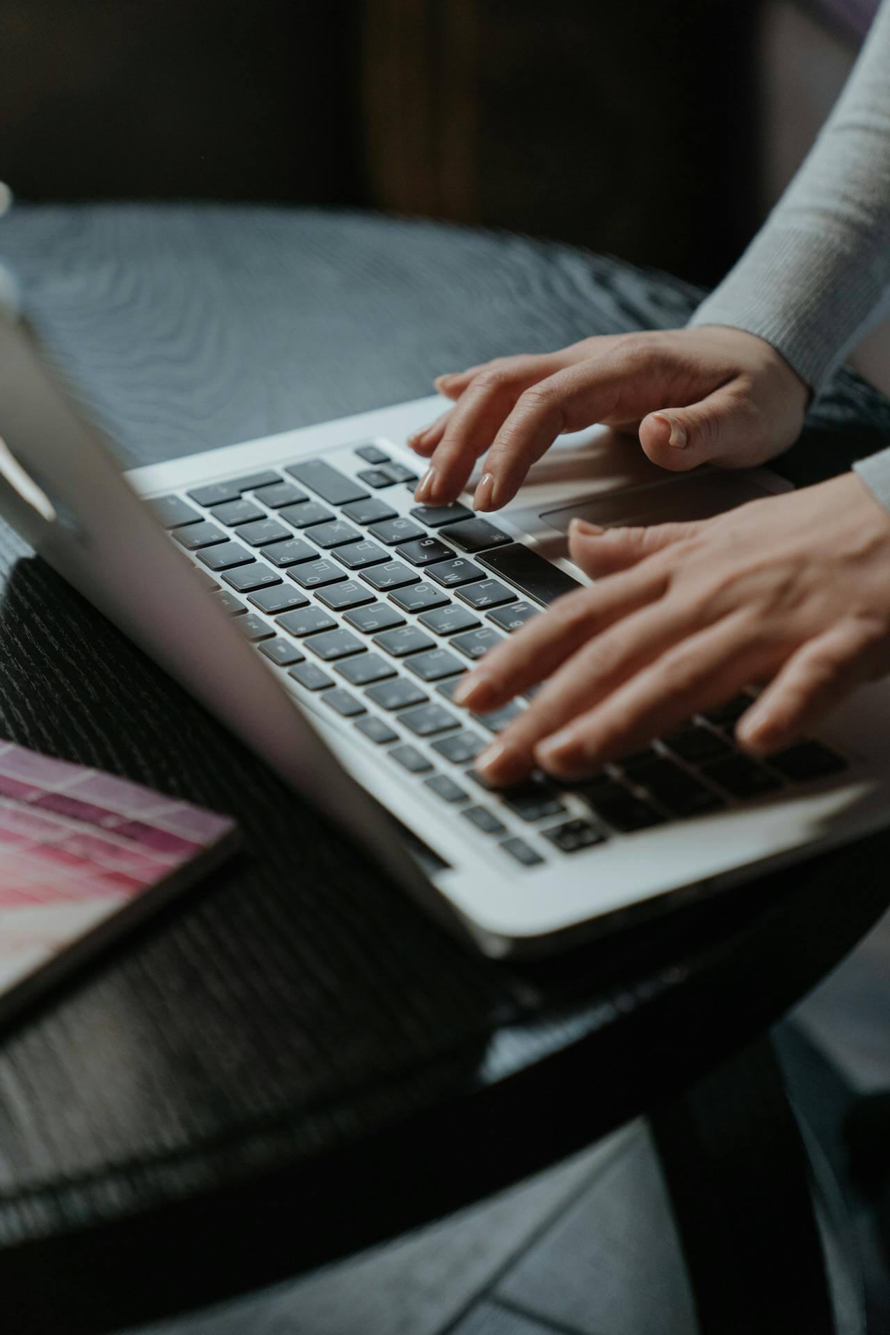 A person focused on typing on a laptop computer, with hands positioned over the keyboard.